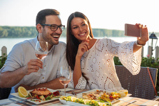 istock Smiling happy young couple posing for a selfie, eating dinner in a riverside restaurant 1169560730