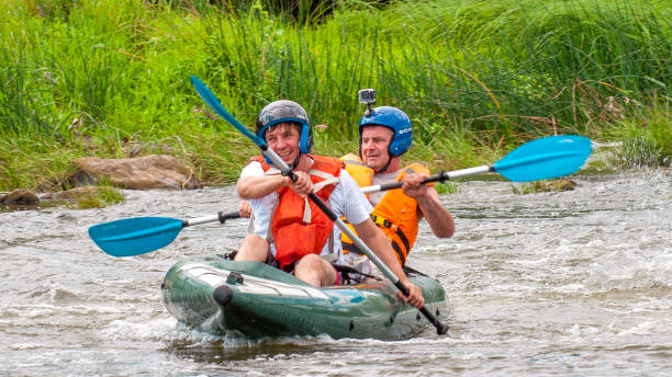 myhiya, ucrania - 17 de agosto de 2019: viaje de rafting. dos remeros están haciendo rafting por el río en un bote inflable de goma. el concepto de comunicación de generaciones, actividad física de los ancianos. - sports team sport rowing teamwork rafting fotografías e imágenes de stock