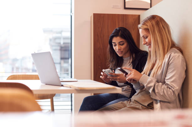 istock Two Young Businesswomen In Meeting Around Table In Modern Open Plan Workspace 1169564703