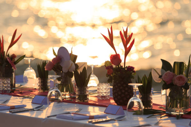 istock Close up dinner table tropical style set on the beach in sunset time Thailand. Beautiful delicate wedding decoration with tropical flowers and fruits. Wedding setting table on the beach. 1169566072
