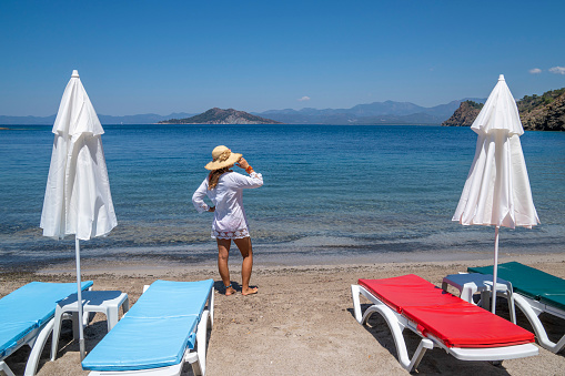 Colorful chairs and tables of Greek tavern by waterfront at sunny day. Vacations in Greece, summer, restaurant, outdoor dining, port, marina, yachts and boats, Mediterranean relax, Cyclades and Aegean islands. Selective focus, blurred background.