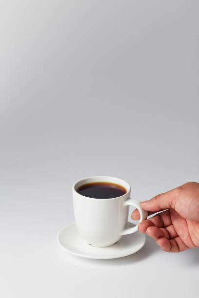 istock Hand holding a white cup of coffee on gray 1169586487