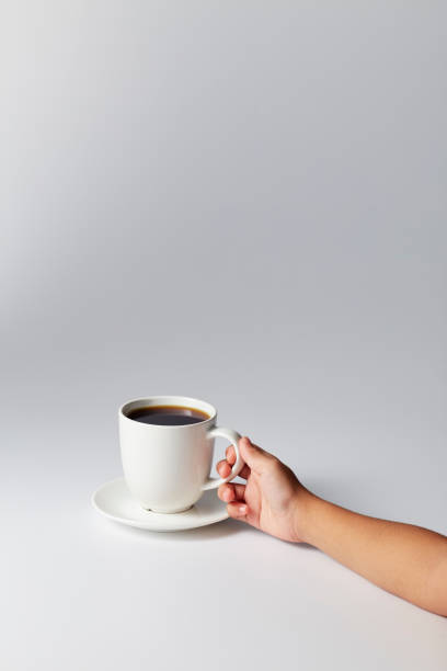 istock Hand holding a white cup of coffee on gray 1169586499