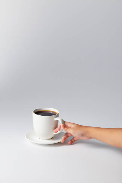 istock Hand holding a white cup of coffee on gray 1169586565