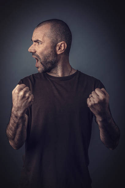 istock Angry Man Clenching Fists While Looking Away Against Gray Background 1169588746
