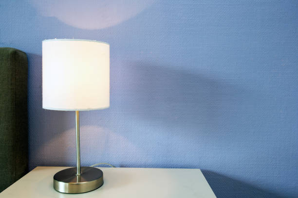 Lamp night light on a night stand with blue wall, space for text