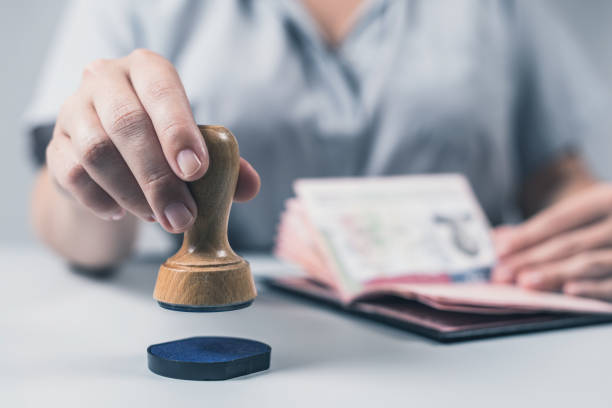 imigração e controle de passaportes no aeroporto. o oficial de controle da beira da mulher põr um selo no passaporte dos e.u. do cidadão americano. conceito - alfândega edifício de transportes - fotografias e filmes do acervo