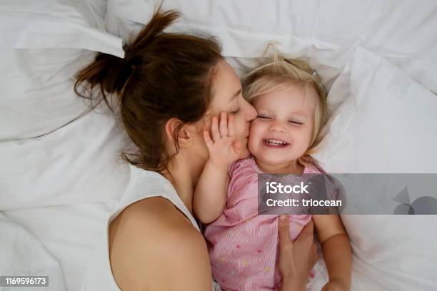 Madre Y Su Bebé Abrazo En La Cama Adorable Bebé Rubia Y Su Madre  Divirtiéndose Feliz