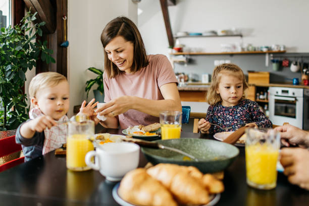 istock Young mom is helping her two kids eating their breakfast 1169598986