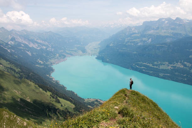 View along a mountain ridge above valley and lake to hiker She is standing on a summit on the Hardergrat, Interlaken lake thun stock pictures, royalty-free photos & images