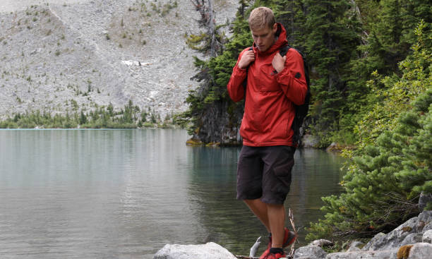 istock Young man explores alpine lakeshore in mountains 1169607955