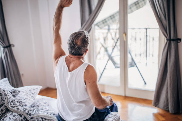 istock Senior man sitting on bed and stretching 1169610049