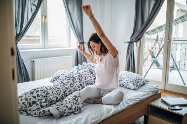 istock Woman sitting on bed and stretching 1169610413