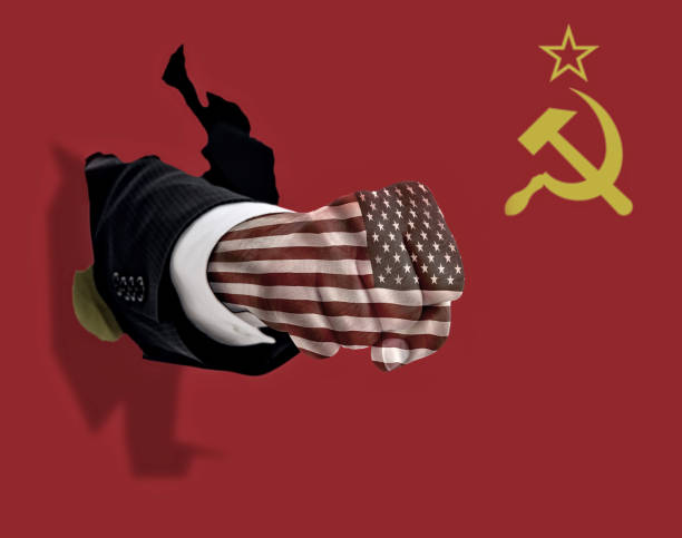 American and Russian Trade War Symbolism with Fist Punching Fight on White Background This is a conceptual photo of an American fist punching through a Russian flag fist human hand punching power stock pictures, royalty-free photos & images