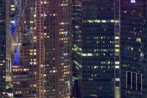 istock Pattern of office buildings windows illuminated at night. Lighting with Glass architecture facade design with reflection in urban city, Downtown Singapore City in financial district. 1169618153
