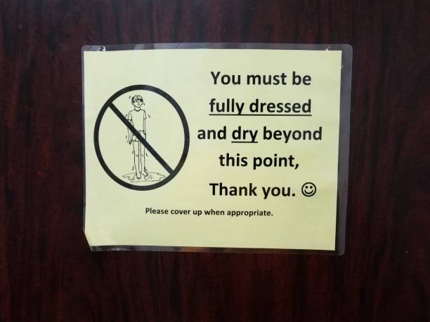 istock you must be fully dressed and dry beyond this point sign on door 1169618171