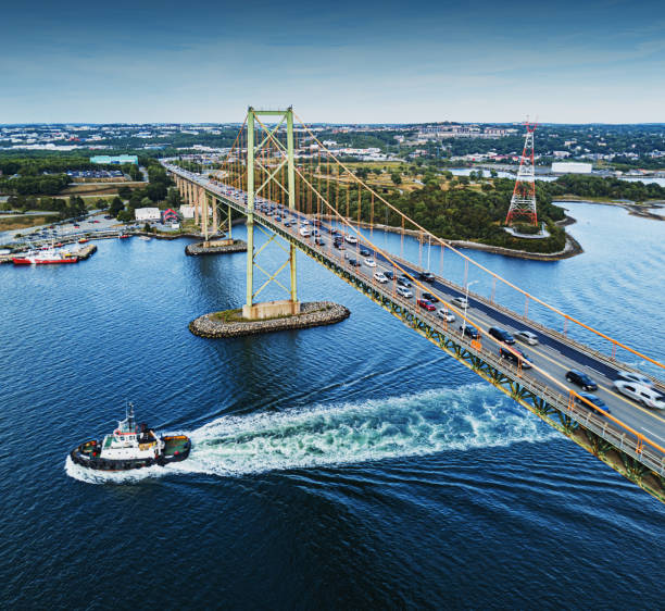 Aerial View of MacKay Bridge A tugboat beneath rush hour traffic on the MacKay Bridge, Halifax Harbour. maritime provinces stock pictures, royalty-free photos & images