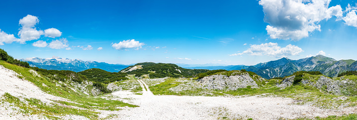 Tourist path in Slovenia mountains near Vogel. Path of top of mountain, green grass, tress, blue sky. Hiking in Europe. Triglav national park, Julian Alps