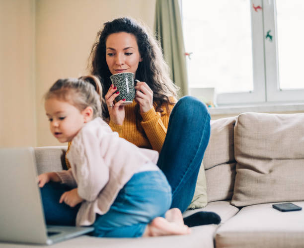 istock Mother and daughter using laptop on sofa 1169621703