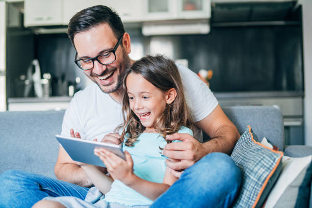 The sofa is our happy Young father and his cute small daughter having fun with digital tablet on couch. one parent stock pictures, royalty-free photos & images