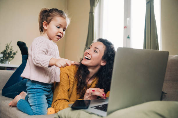 istock Mother and daughter using laptop on sofa 1169621827