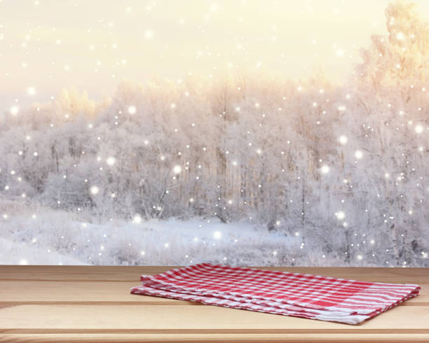 istock Empty wooden table top with a towel on blurred winter backdrop with snowflakes. 1169623176