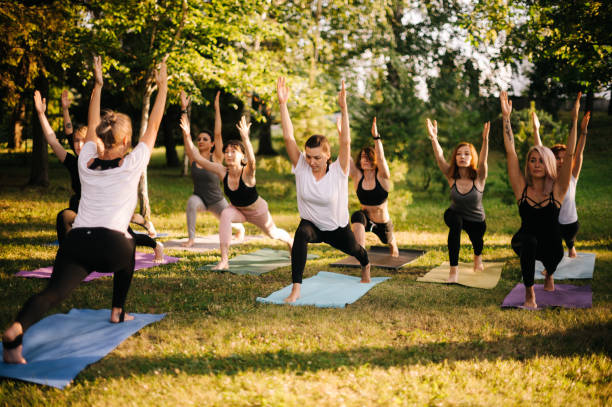 groupe de jeunes femmes sportives belles pratiquant la leçon de yoga avec l'instructeur - yoga class caucasian young adult group of people photos et images de collection