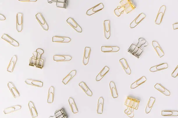 Set of silver and gold paper clips on light grey background. Flat lay. Office and business concept.