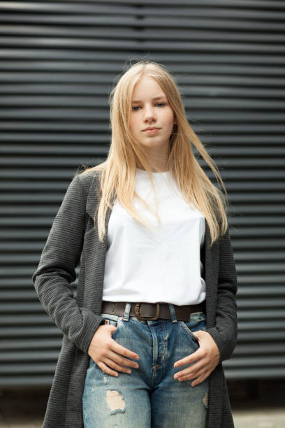 nahaufnahme outdoor-porträt eines 13-jährigen blonden teenager-mädchens in einer grauen jacke und jeans - teenage girls blue eyes adolescence teenager stock-fotos und bilder