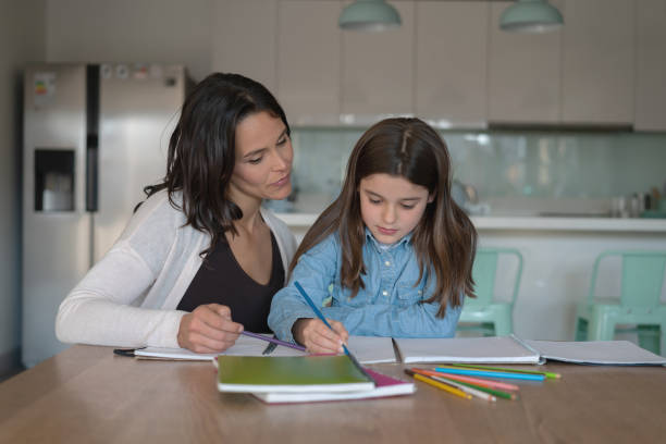 istock Focused daughter and mommy doing homework writing on notebooks 1169630694