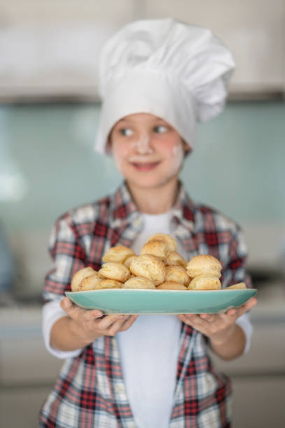 istock Focus on foreground of fresh biscuits on plate that little chef is holding 1169631814