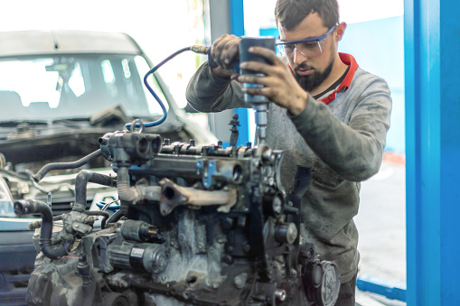 Young technician repairing car engine in car service