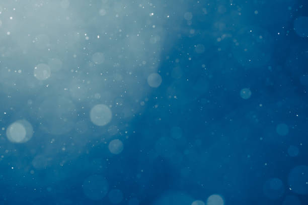istock blue light background with snowflakes particles 1169634340