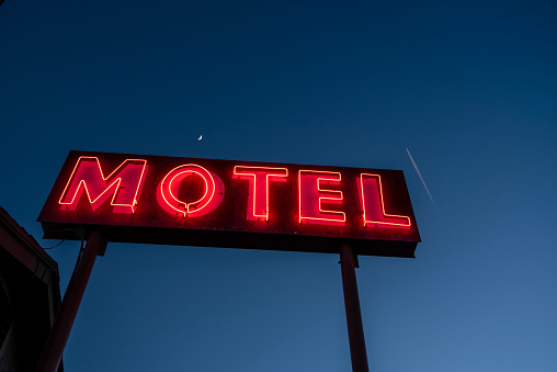 illuminated neon motel sign red letters dark blue sky