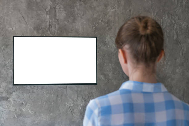 istock Woman watching flat smart led TV with white blank screen - mockup concept 1169638290