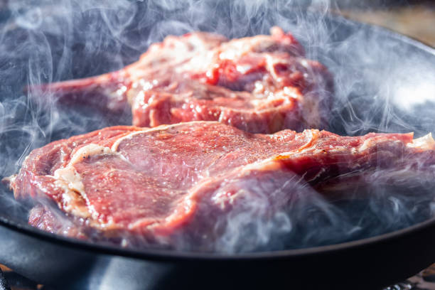 istock Smoke and steam rise from a beaf steak on grill pan 1169639355