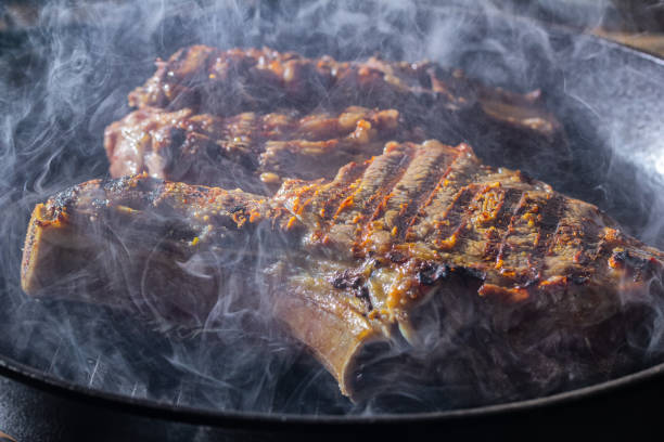 istock Smoke and steam rise from a beaf steak on grill pan 1169639513