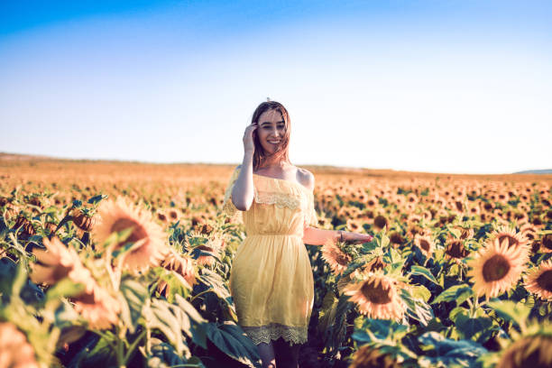 Young Asian woman with curly hair in a field of sunflowers at sunset. Portrait of a young beautiful asian woman in the sun. Summer.