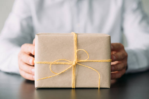 istock corporate birthday party beige paper gift box hands 1169655385