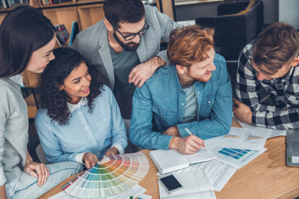 istock Startupers working together at office sitting holding palette taking notes smiling happy top view 1169656032