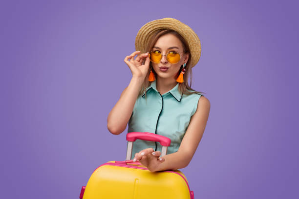 istock Trendy young traveler with suitcase pouting lips 1169656515
