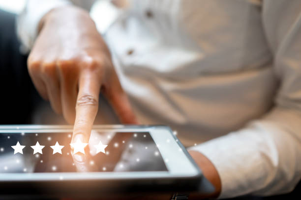 istock close up on businessman hand pressing on digital tablet screen with five star rating feedback and press good level rank for give score to provider service , technology business concept 1169656849