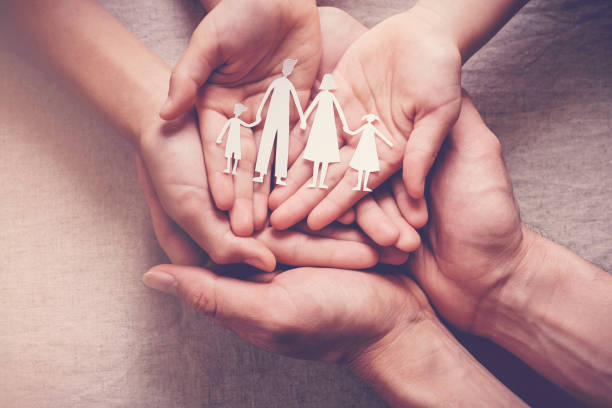 Adult and children hands holding paper family cutout, family home, foster care, homeless charity support concept Adult and children hands holding paper family cutout, family home, foster care, homeless charity support concept sheltering photos stock pictures, royalty-free photos & images