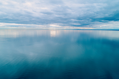 Minimalist aerial seascape. Overcast sky over calm and smooth water surface