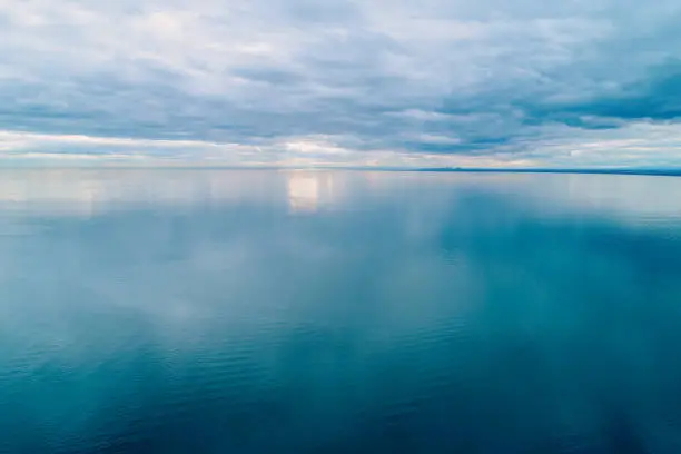 Photo of Minimalist aerial seascape. Overcast sky over calm and smooth water surface