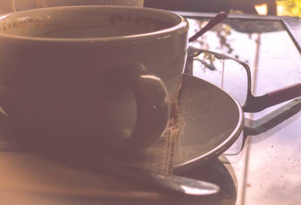 Abstract  vintage  style  empty  cup cofee  with reflection on table eyeglasses .