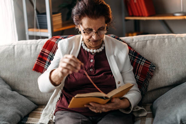 istock Old woman sitting on sofa and reading a book 1169673903