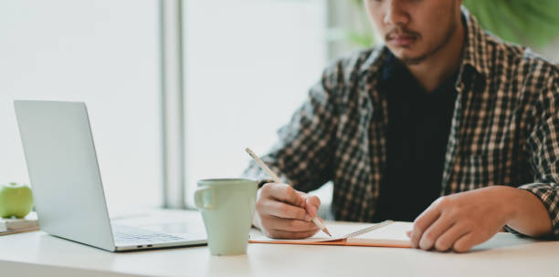 istock Motivated male freelance writing his idea on notebook 1169673930
