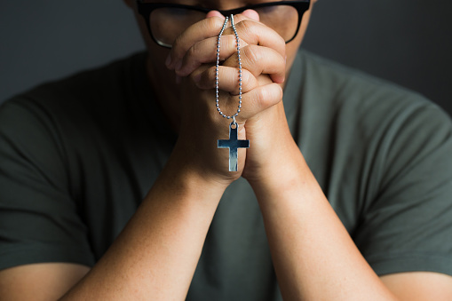 Man praying hands holding a rosary.Religious concepts