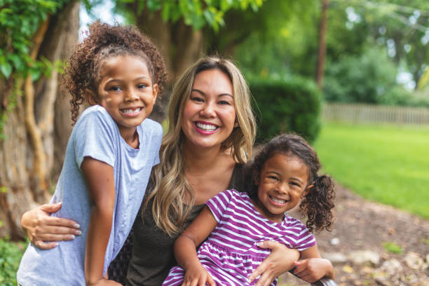 madre china asiática con dos hijas de etnia mixta china y afroamericana en un entorno verde exuberante patio trasero posando para retratos sonriendo y siendo tonto - acogida temporal fotografías e imágenes de stock